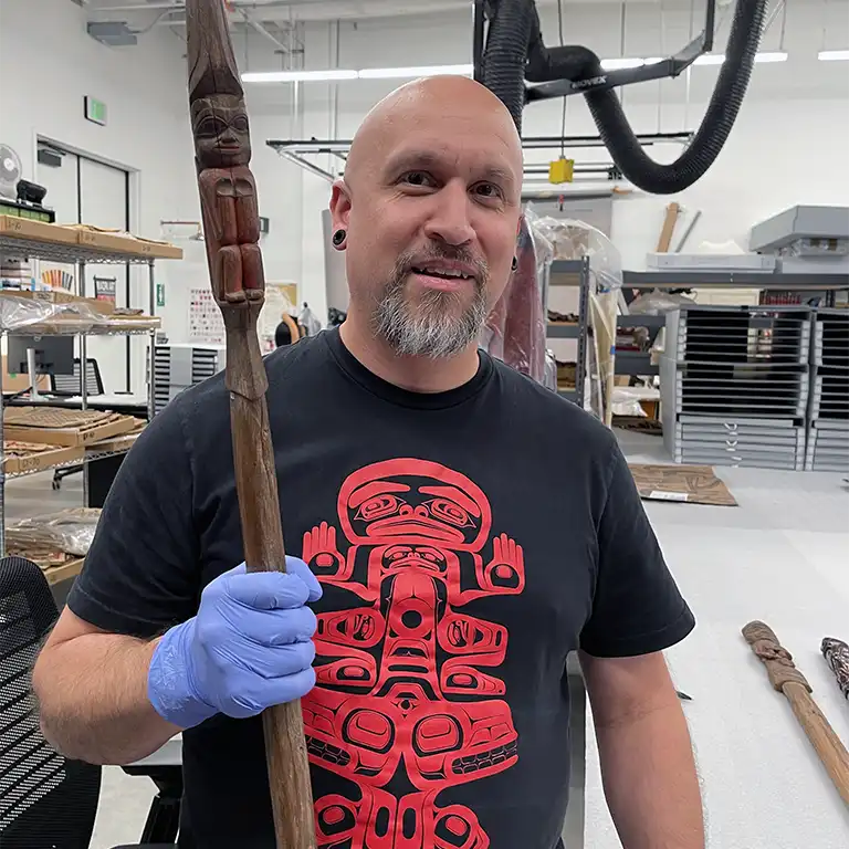 Thumbnail size image of Kaa Shaayi holding a Tlingit staff decorated with Formline, studied in 2023 at the Bill Holm Center in Seattle Washington